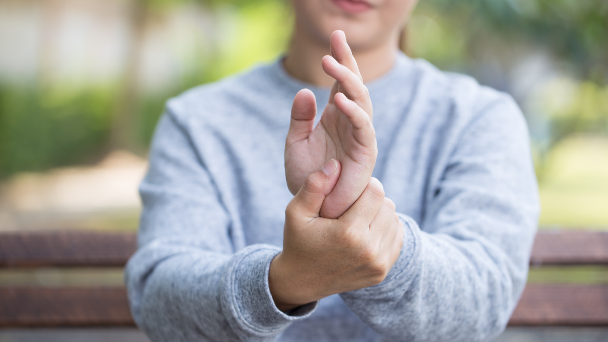 A woman holding her wrist, signifying hand or foot pain caused by peripheral neuropathy.